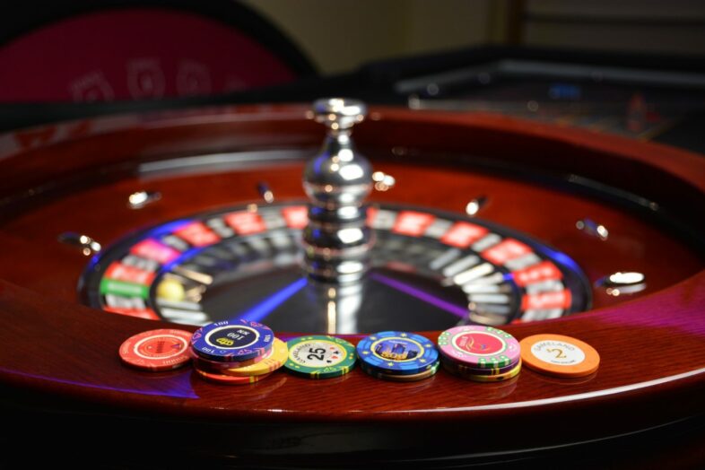 Online-Glücksspiel: Roulette-Casinos – darum ist die Einhaltung der Regeln so wichtig! 1 Verschiedene Jetons liegen auf dem Rand eines Roulette-Kessels